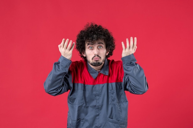 Vista frontale lavoratore maschio in uniforme su sfondo rosso colore uniforme strumento lavoratore meccanico lavoro casa foto