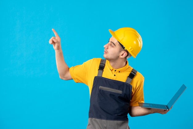 Front view of male worker in uniform with laptop on a blue 