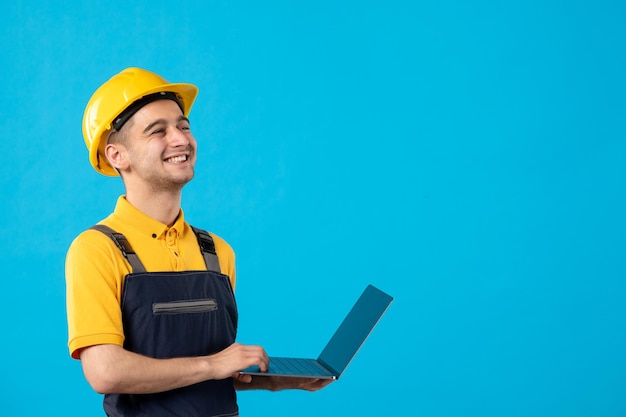 Front view of male worker in uniform with laptop on blue 