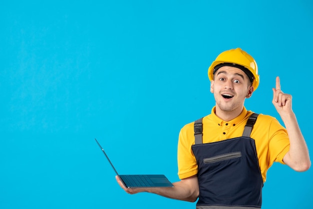 Front view of male worker in uniform with laptop has an idea on blue 