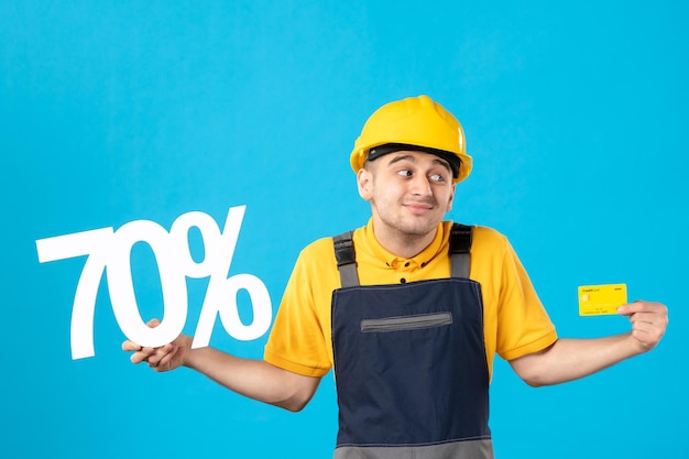 Front view of male worker in uniform with writing and credit card on blue 