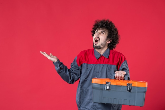 Front view male worker with tool case on red background photo color worker house job emotion uniform instrument