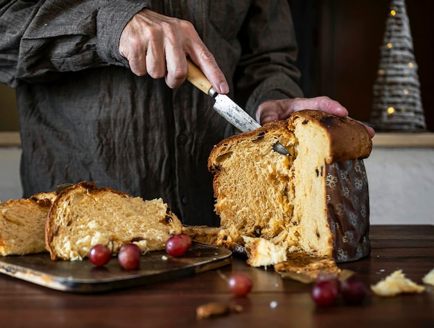 Front view of man cutting a panettone for Christmas dinner at home Christmas candy
