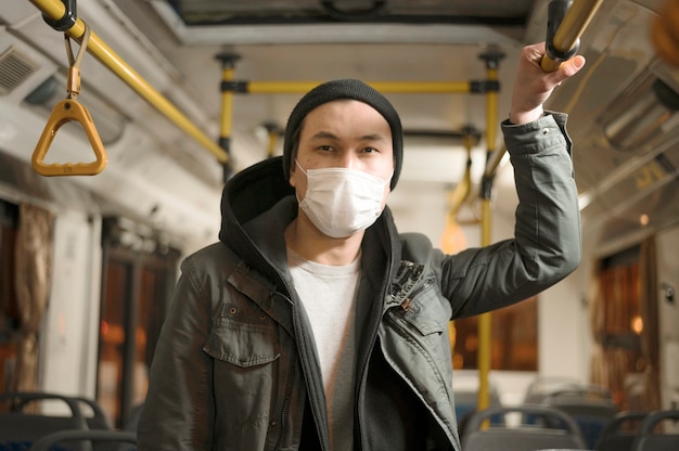 Photo front view of man posing with medical mask on the bus