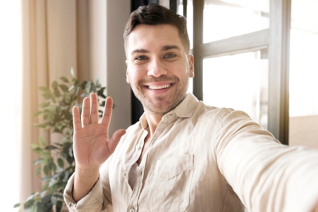 Front view man taking selfie with hand up