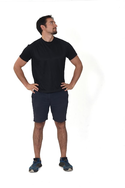 Front view of man wearing sportswear shorts looking away and arms akimbo isolated on white background