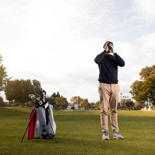 Vista frontale dell'uomo con il binocolo sul campo da golf