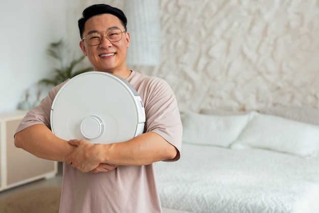 Front view man with robotic vacuum cleaner at home