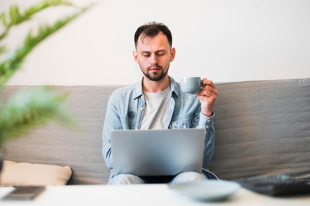 Foto vista frontale dell'uomo che wotking al suo computer portatile