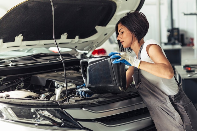 Photo front view mechanic female changing oil