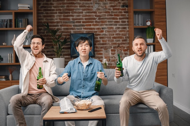 Front view of men watching a football game on tv and drinking a beer