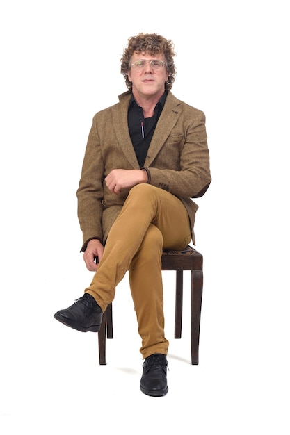 Front view of middle aged man with blazer sitting on chair on white space,