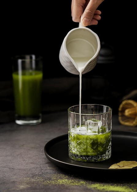 Front view of milk poured in matcha tea glass with ice cubes