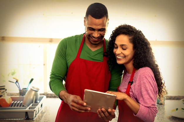 Front view of a mixed race couple in their kitchen at Christmas, using a laptop computer