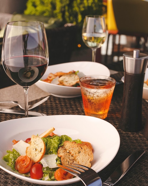 A front view morning table along with fresh vegetable salad glasses of wine on the designed elegant table during daytime city