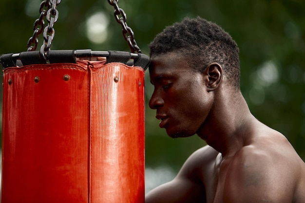 Front view of muscular black boxer punching towards camera with a deep and intense face outdoor. Boxing and Training Concept