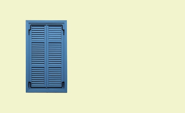 Front view of neat blue window with closed striped shutters on beige stucco wall