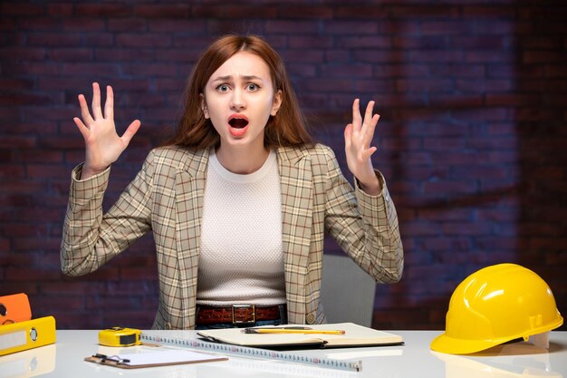 Photo front view nervous female worker in construction site behind table agenda job engineer business manager corporate plan working builder