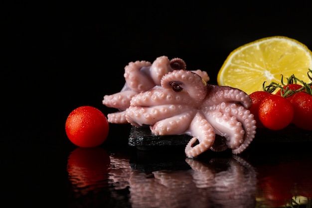 Photo front view octopus with lemon and tomatoes