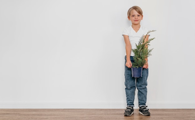 写真 コピースペースと植物のポットを保持している少年の正面図