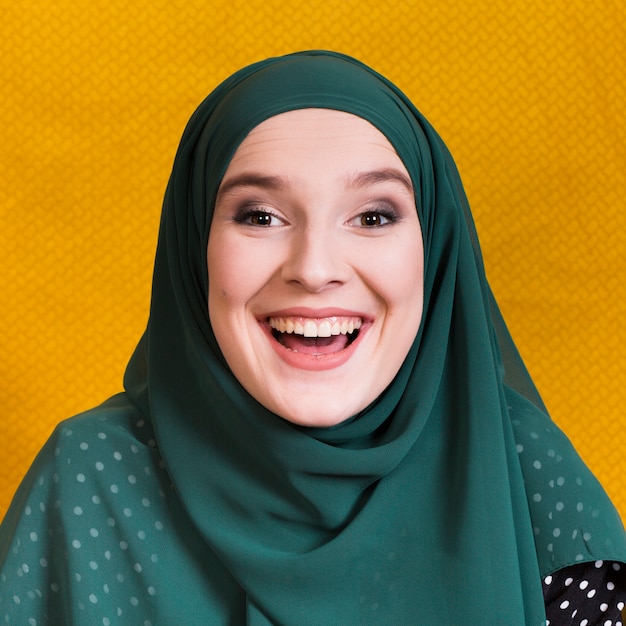 写真 黄色の背景に陽気なアラビアの女性の正面図