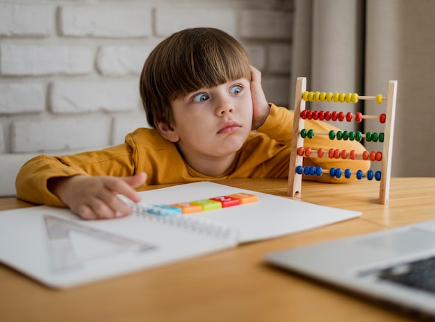 写真 自宅のラップトップから学びながらショックを受けた子供の正面図