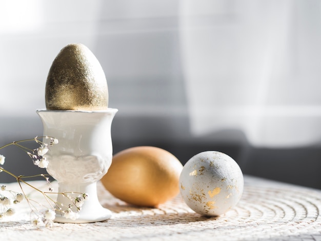 Вид спереди золотого пасхального яйца в держателе с копией пространства
