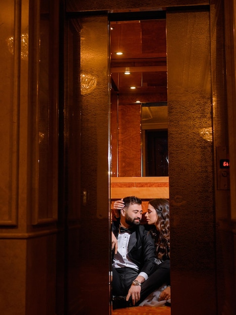 Фото Вид спереди на роскошную деревянную дверь с зеркалом с отражающими молодоженов в праздничных нарядах, которые сидят на полу и смотрят друг на друга в день свадьбы