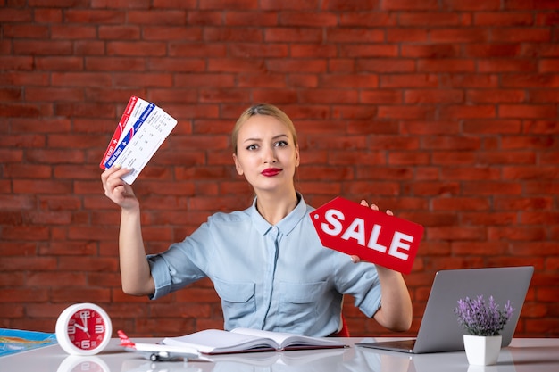 写真 チケットと販売のネームプレートを保持している彼女の職場の後ろに座っている旅行代理店の正面図グローバルマネージャー屋内代理店職業観光マップ