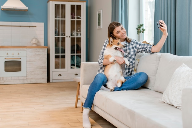 彼女の犬と一緒にselfieを取ってソファの上の女性の正面図