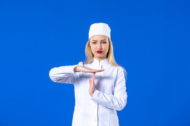 Фото Вид спереди молодой медсестры в медицинском костюме на синей стене