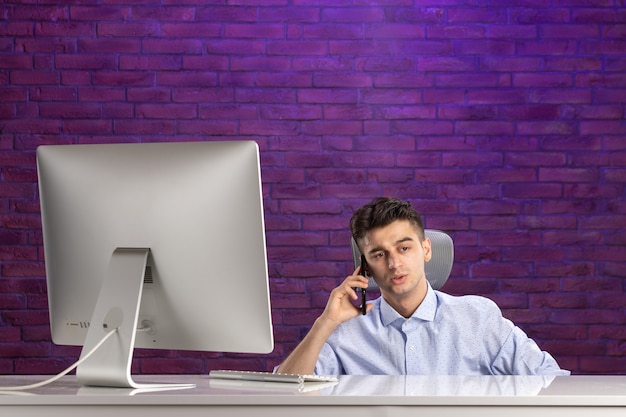 Front view office worker behind office desk talking at phone