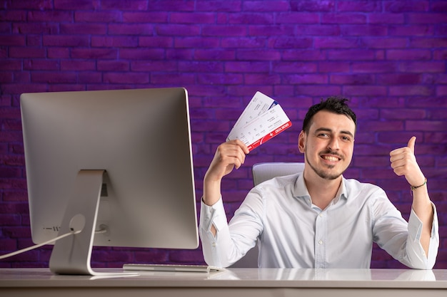 Front view office worker sitting behind his working place and holding tickets