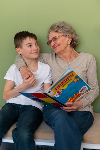 Photo front view old woman and boy reading comics