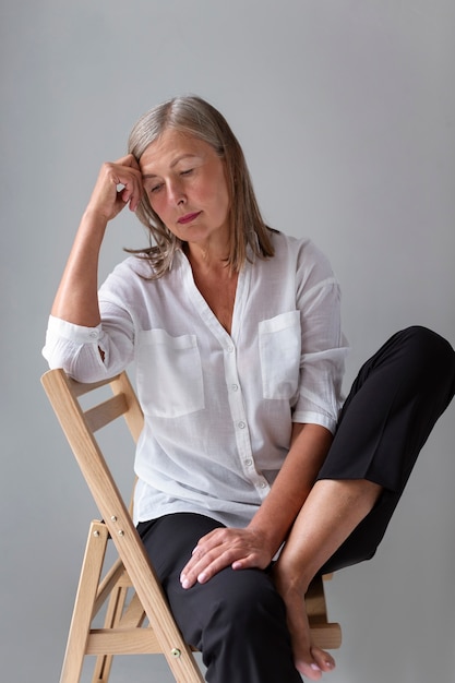 front view old woman posing on chair