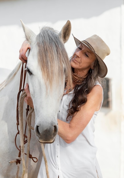 Foto vista frontale dell'anziano agricoltore femminile con il suo cavallo al ranch