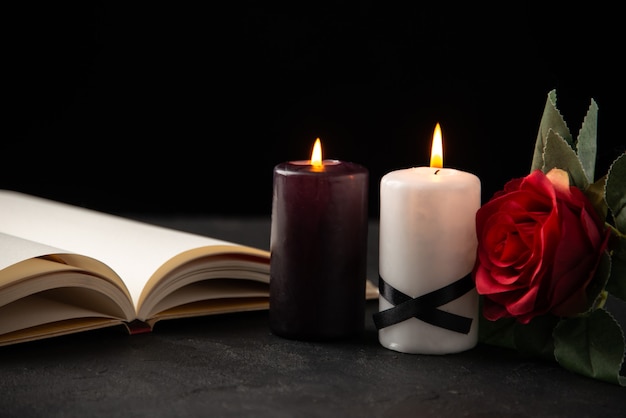 Front view of open book with candles and rose on black