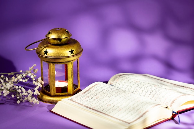 Photo front view open quran next to candleholder