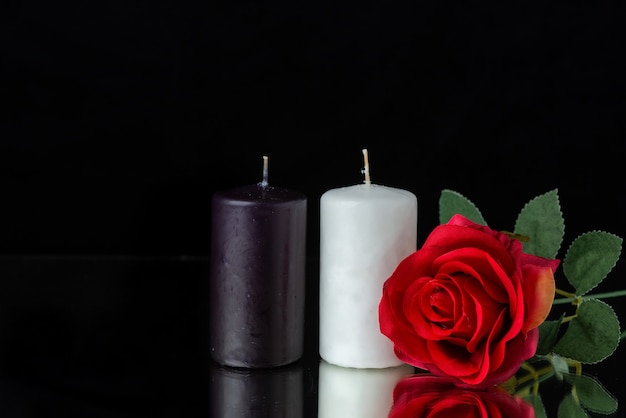 Front view of pair of candles with red rose on black