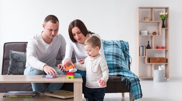 Photo front view of parents and child at home playing