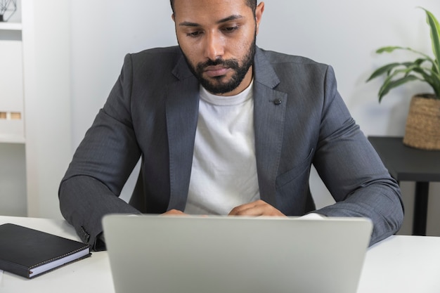 ノートパソコンを使用して自宅で働く物思いにふける若いアフリカ系アメリカ人ビジネスマンの正面図