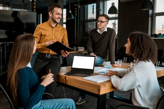 Front view of people with laptop and papers during a meeting in the office