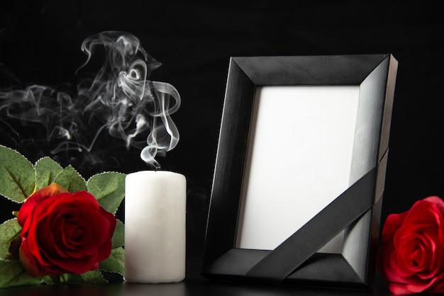 Front view of picture frame with candle and red flowers on dark