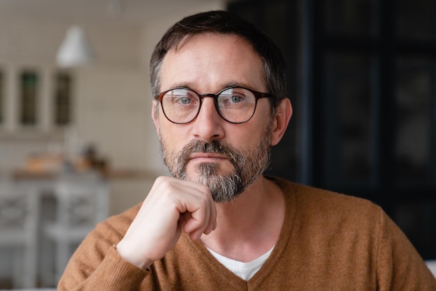 Front view portrait of a confident thoughtful pensive Caucasian middleaged mature man teacher father freelancer wearing glasses looking at camera at home