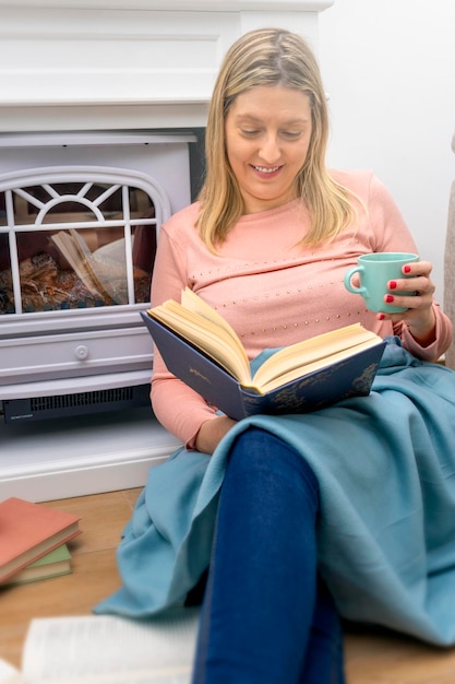 Front view portrait of a girl reading a book sitting at floor at home