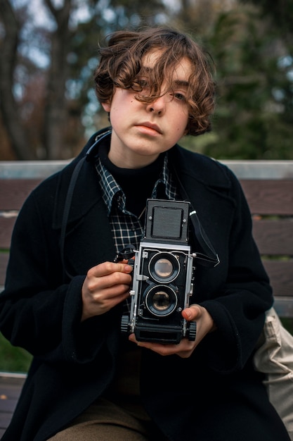 Front view portrait of non binary person holding a retro camera