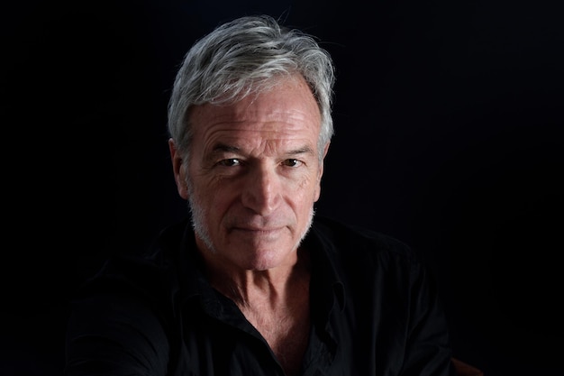 Front view portrait of senior man on black background