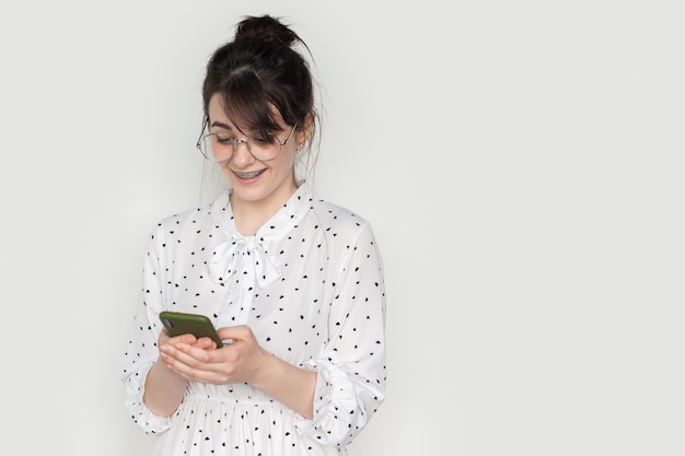 Front view portrait of young smiling woman using mobile phone isolated against white background with copy space