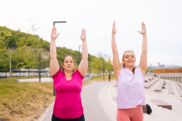 Front view of positive fitness female trainer have personal training with overweight young woman