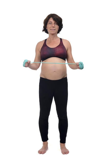 Vista frontale di una donna incinta in piedi facendo bande di resistenza all'esercizio su sfondo bianco